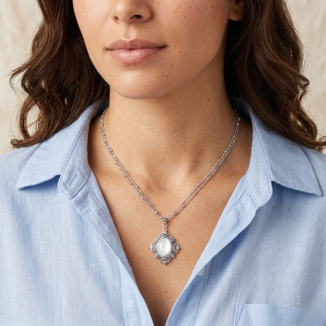 Woman wearing a silver necklace with a gemstone and blue crystal pendant, close-up of the necklace.