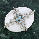 Aquamarine Crystal Mother Of Pearl Filigree Pin on green marble stone surface