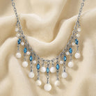 Aquamarine Crystal Mother Of Pearl Bib Necklace resting on white fabric