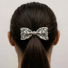 Woman with dark hair wearing our Antiqued Paws & Bones Bow Barrette Hair Clip