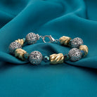 Twisted Bead Filigree Puff Ball Fire Polished Green Bead Link Bracelet resting on teal fabric surface