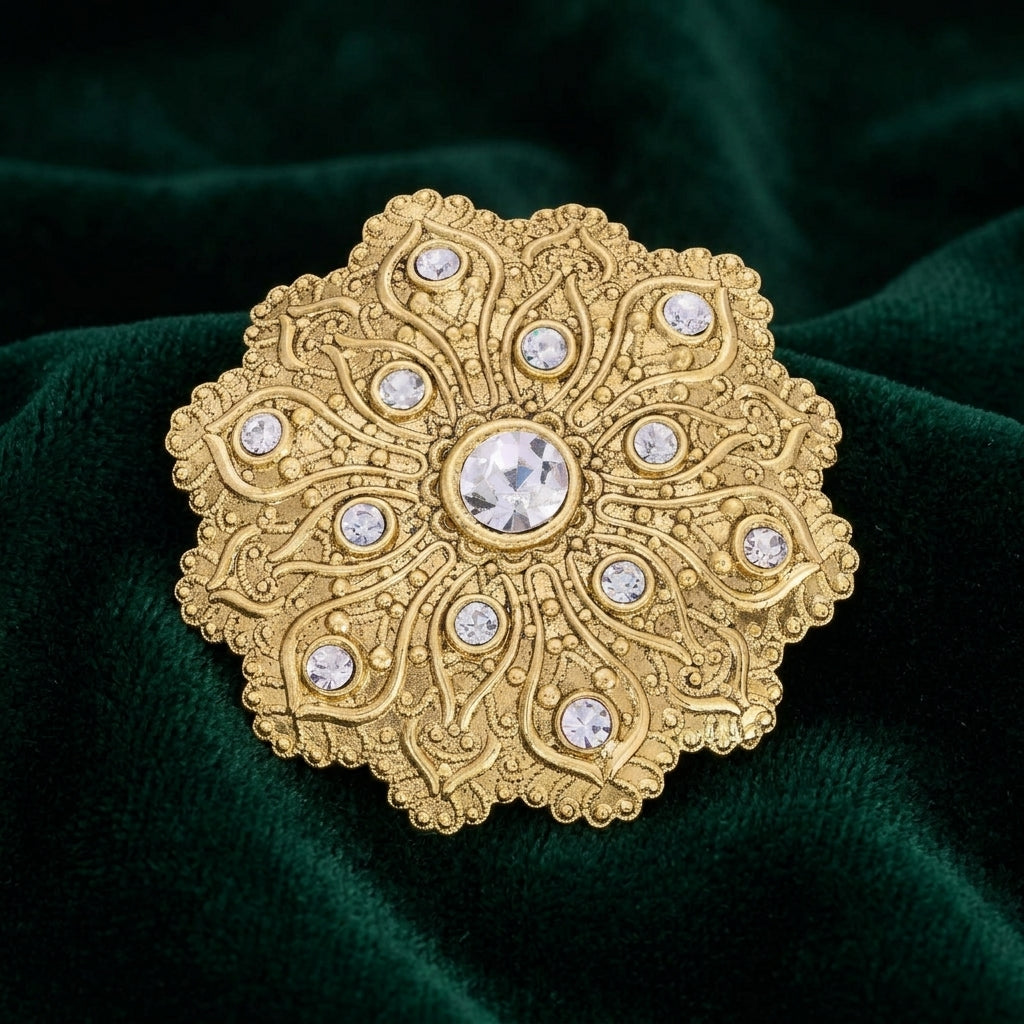 Gold tone iImperial Flower Crystal Brooch with clear crystals resting on dark green fabric