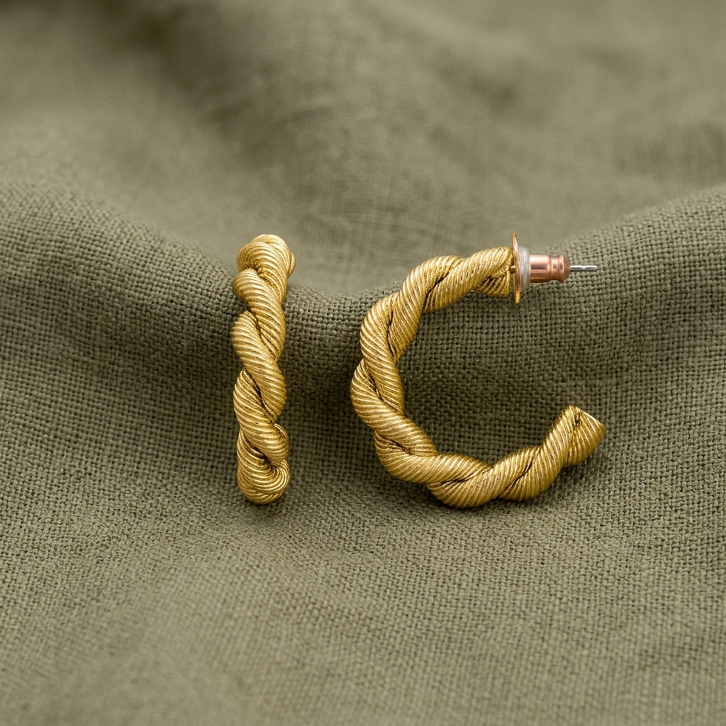 Gold tone Spiral Shaped Hoop Post Earrings displayed on a textured olive green fabric background.