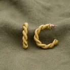 Gold tone Spiral Shaped Hoop Post Earrings displayed on a textured olive green fabric background.