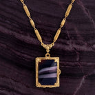 Purple stone Ol' Family Album Stone Locket Necklace resting on dark stone surface
