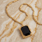 Black Ol' Family Album Stone Locket Necklace resting on beige stone granite surface