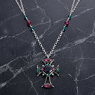 Monarch Emerald & Amethyst Crystal Black Octagon Stone Cross Pendant Necklace resting on black marble stone surface