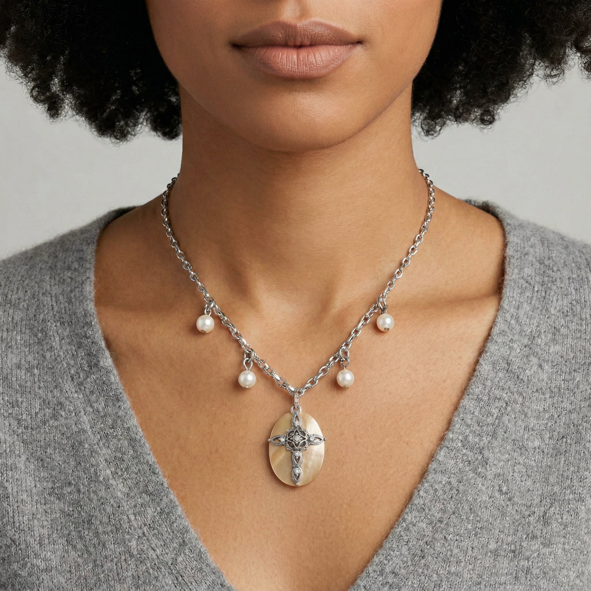 Woman in a gray top wearing our Faux Pearl Oval Disk Cross & Crystal Pendant Necklace
