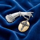 Belle Epoch Ladies Crystal Hand Oval Disk Cross & Crystal Pin resting on blue fabric
