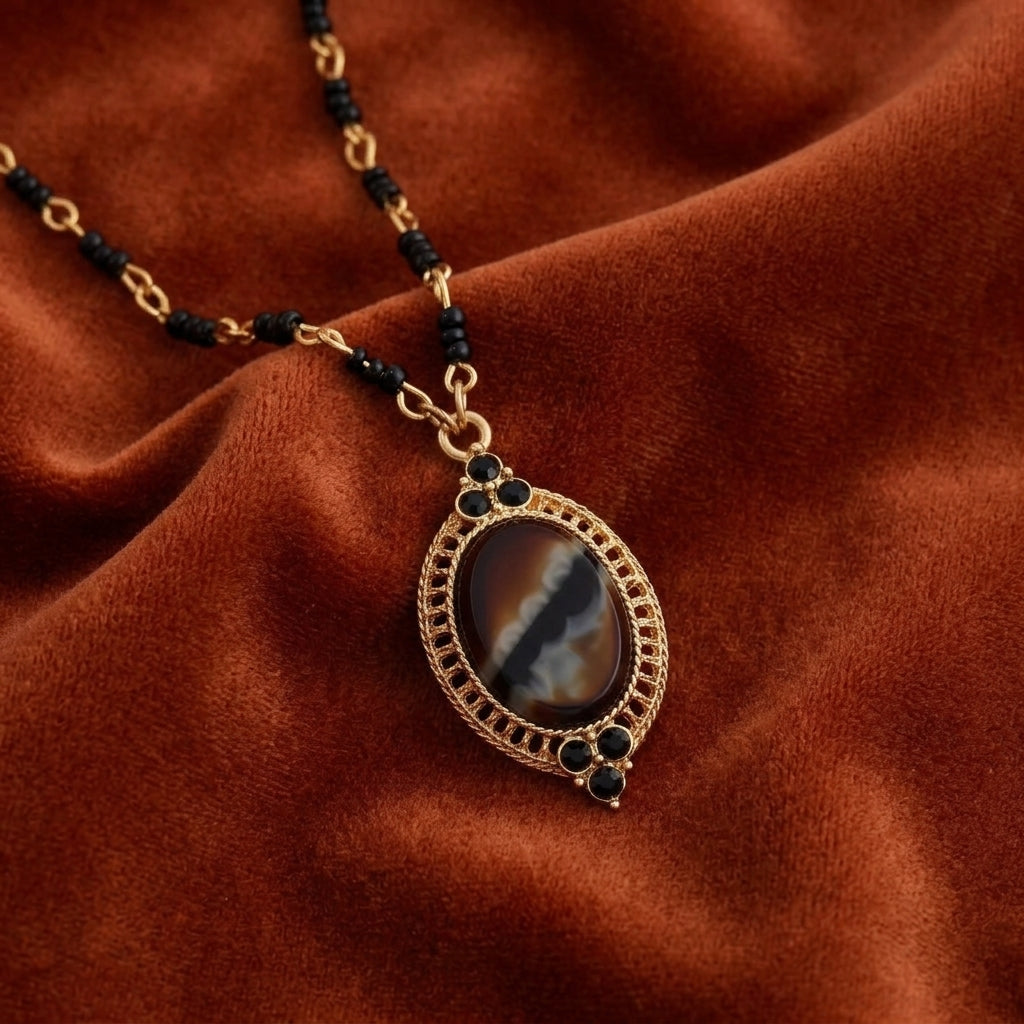 Tigers Eye Glass Stone Pendant Necklace resting on dark orange fabric