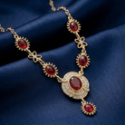 Gold necklace with red crystals on a blue fabric background