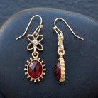 Red Sol Oval Stone Crystal Dangle Earrings on a dark surface