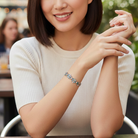 Woman wearing a bracelet seated at an outdoor cafe. 
