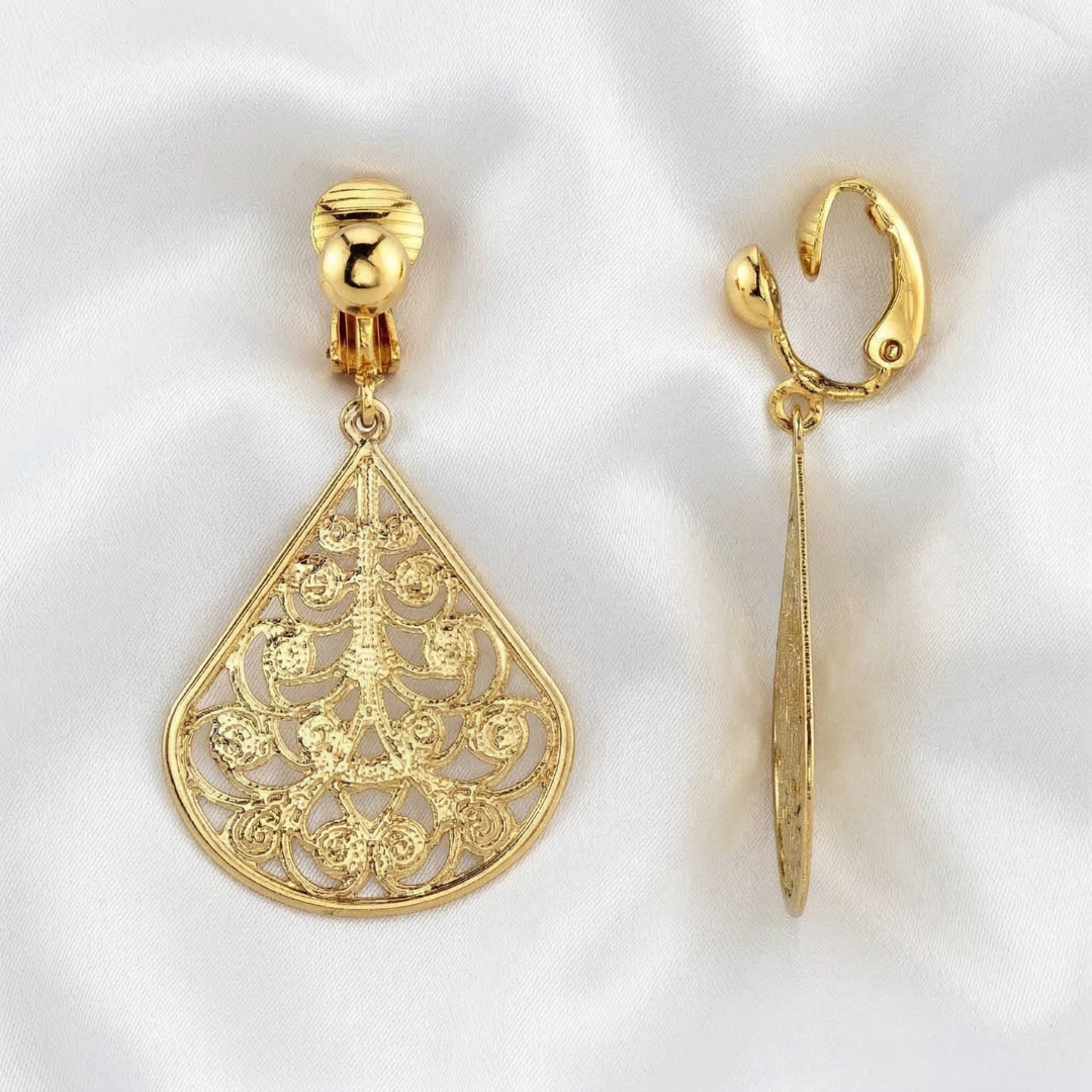 Gold filigree earrings on a white satin fabric background