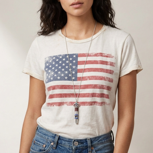 Person wearing a white t-shirt with an American flag design and blue jeans with a red, white and blue crystal accented whistle pendant necklace