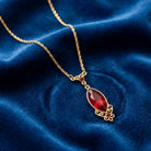 Alluring Siam Red Filigree Pendant Necklace resting on blue fabric