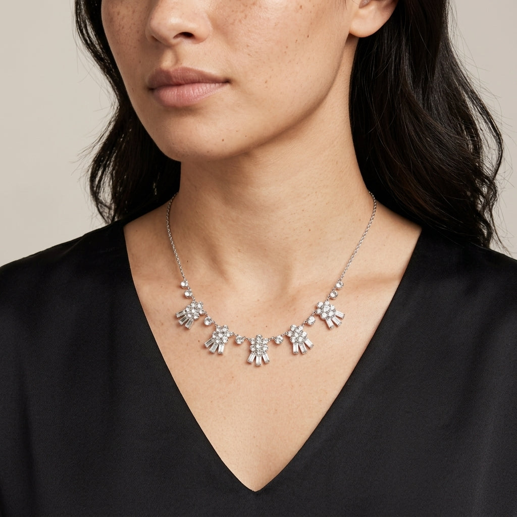 Woman wearing a silver necklace with floral Austrian crystal drop designs on a neutral background
