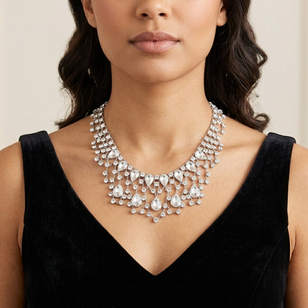 Woman wearing a sparkling vintage Austrian crystal bib necklace with a black dress against a neutral background