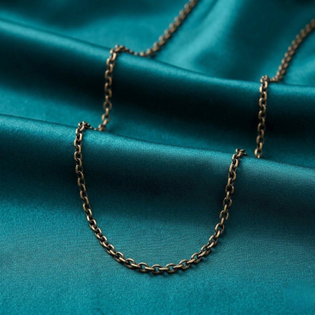 Dark gold tone chain necklace on a teal fabric background