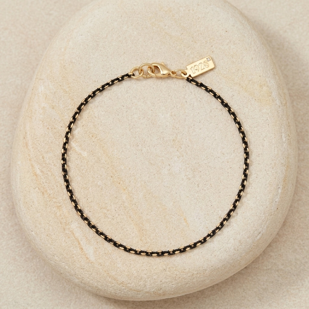 Eclipse Black And Gold & Chain Bracelet resting on a light-colored stone surface