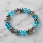 Pink Flower and Blue Bead Crystal Stretch Bracelet resting on marble surface