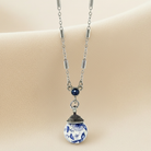 Necklace with a blue and white ceramic pendant on a beige background
