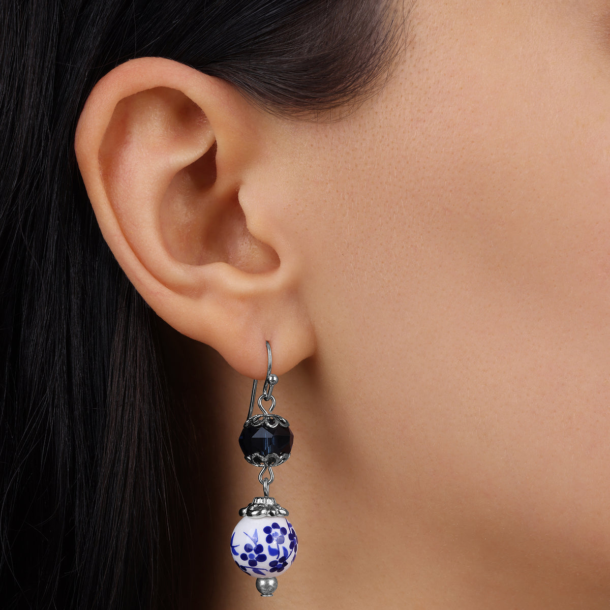 A close-up of a model's ear wearing our Blue Willow Dark Blue And Beaded Dangle Earrings
