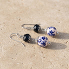 Blue Willow Dark Blue And Beaded Dangle Earrings resting on flat beige limestone