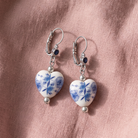 Blue Willow Blue Stone Heart Drop Earrings resting on light pink linen fabric