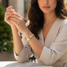 Woman wearing a gold bracelet with a cameo design, sitting outdoors.