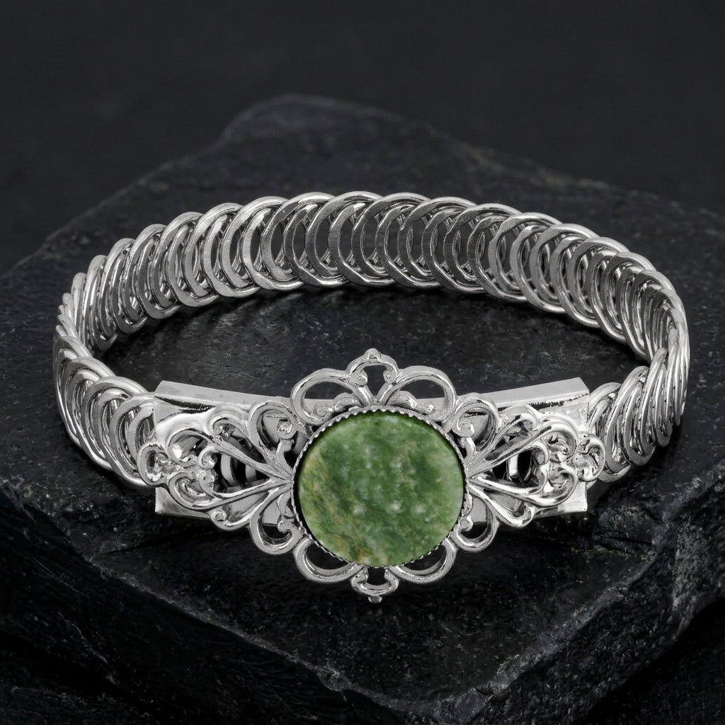Silver bracelet with a green stone on a dark surface