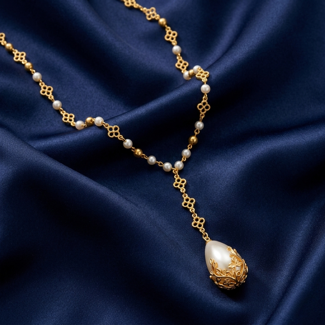Gold and faux pearl necklace on a dark blue fabric background