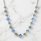 Filigree Puff Bead Blue Crystal Chain Necklace resting on marble surface
