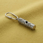 Silver Paws And Bones Whistle Carabiner Key Chain resting on yellow colored felt