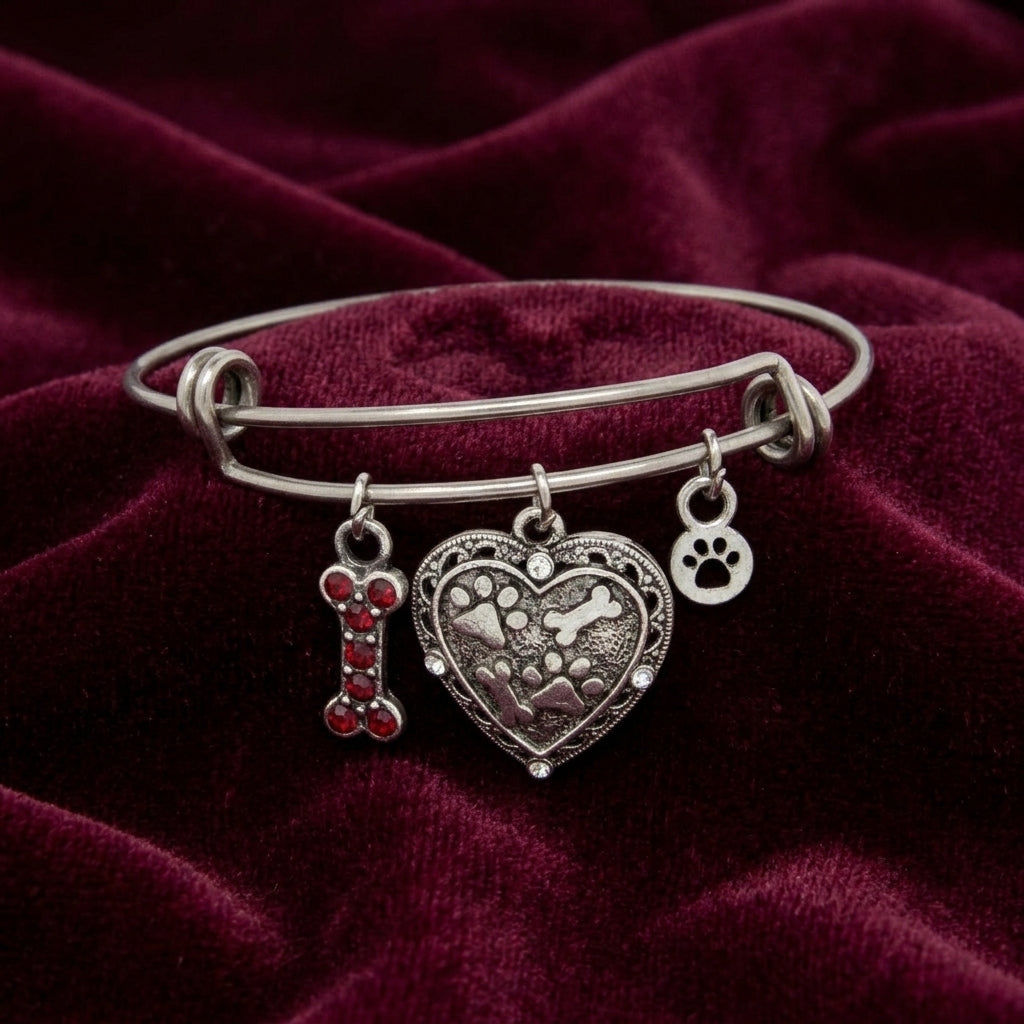 Pewter three charm pet bracelet resting on maroon fabric