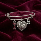 Pewter three charm pet bracelet resting on maroon fabric