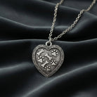 Pewter Heart Paws And Bones Pendant Necklace resting on dark colored fabric