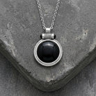 Onyx Cabochon Round Gemstone Pendant Necklace resting on concrete surface