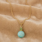 Turquoise Gemstone Round Beaded Drop Necklace on a beige fabric surface
