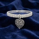 Two Row Rhinestone Crystal Stretch Bracelet With Paws And Bones Heart Charm resting on dark blue fabric 