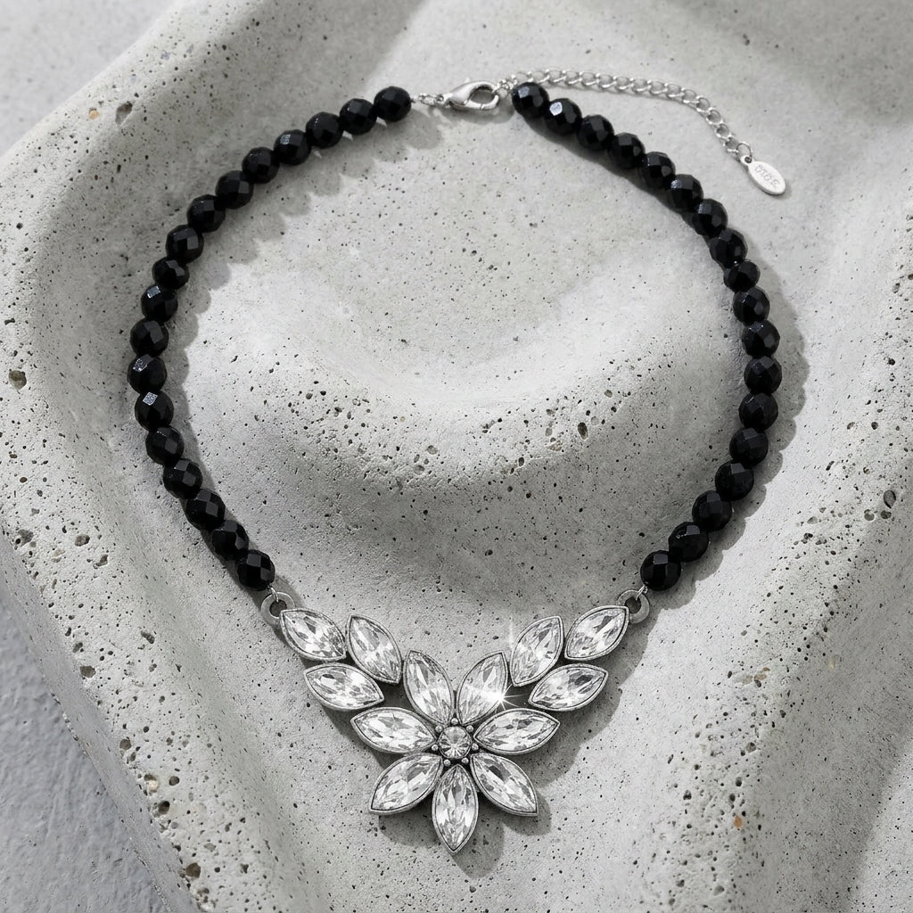 Austrian Crystal Flower & Black Glass Beaded Necklace resting on concrete surface