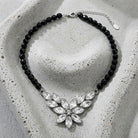 Austrian Crystal Flower & Black Glass Beaded Necklace resting on concrete surface