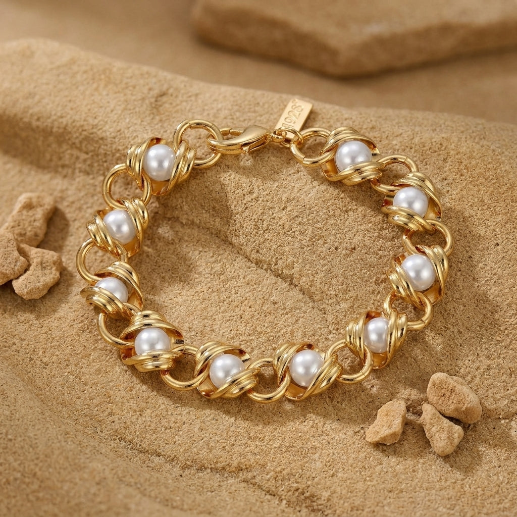 Gold tone chain bracelet with white faux pearls woven through resting on a sandstone surface