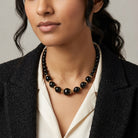 Woman in a dark blazer wearing a Round Black Faceted Beaded Stranded Necklace