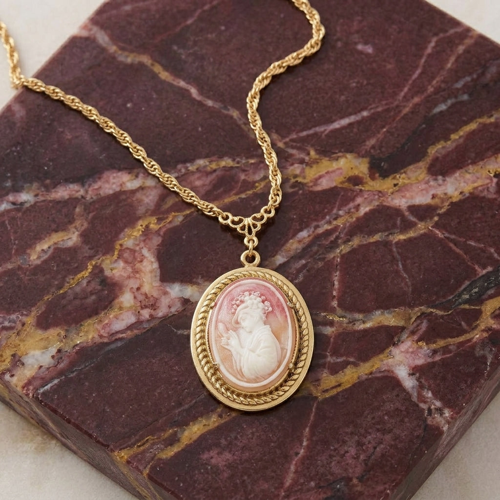 Gold tone necklace that has a carnelian ivory cameo pendant resting on a slab of dark red marble