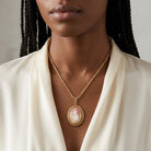 Woman in a white top wearing a gold tone necklace that has a carnelian ivory cameo pendant 