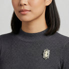 Woman in a dark sweater wearing a black cameo brooch with black crystal accents and a silver tone frame