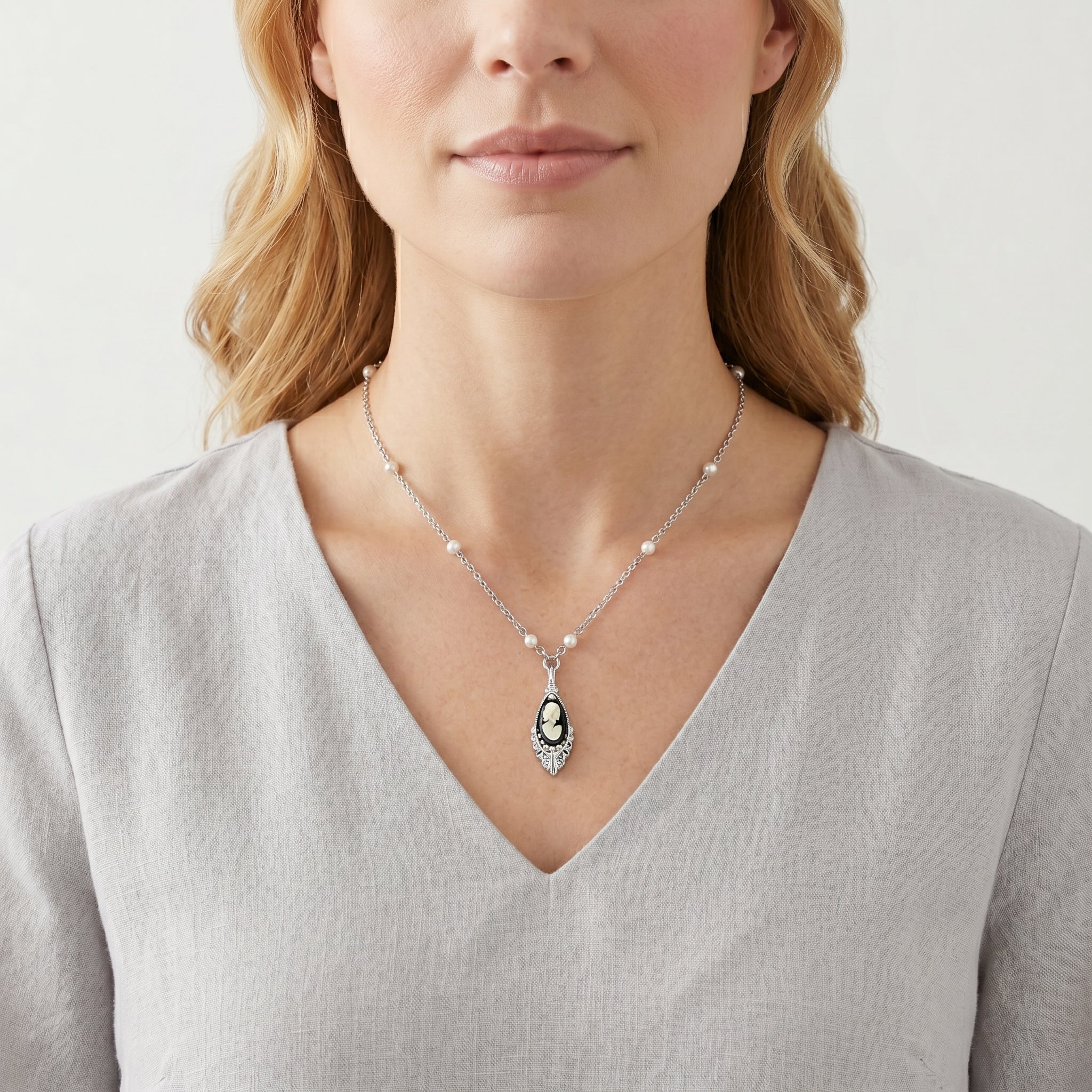 Woman wearing a black cameo pendant necklace with white faux pearls on the chain