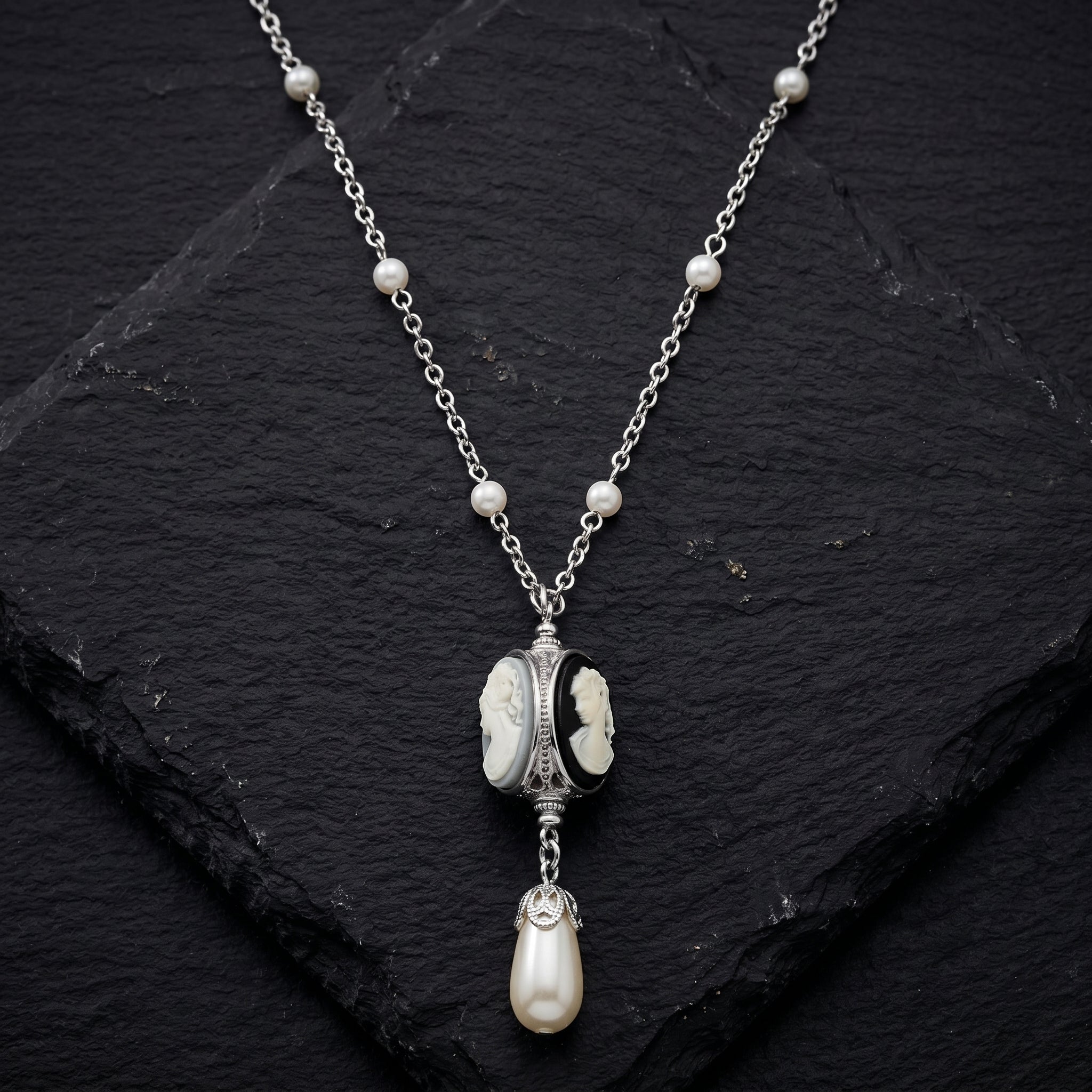 Three cameo spinner pendant necklace with white faux pearls resting on dark stone surface