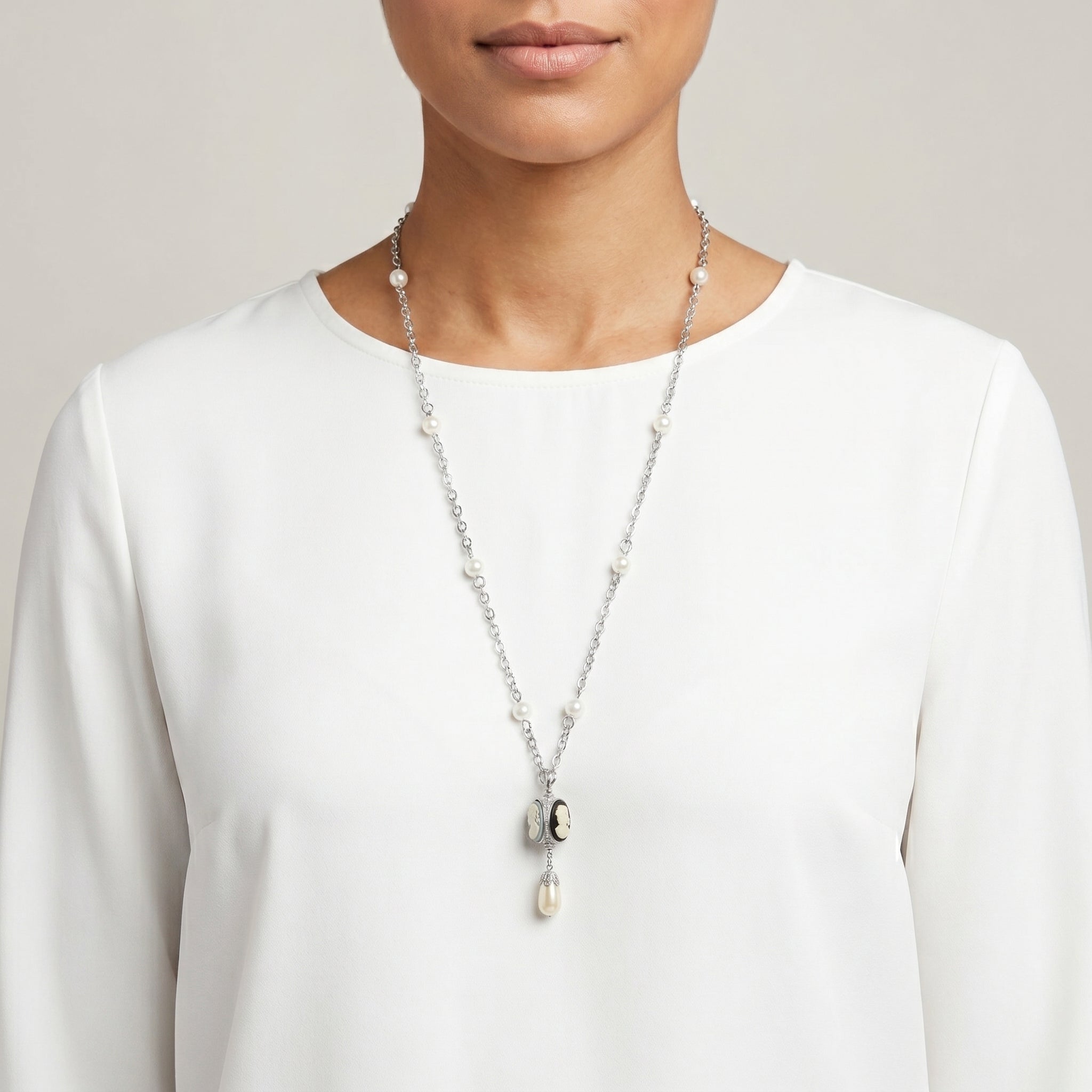 Woman in a white shirt wearing a three cameo spinner pendant necklace that has white faux pearls on a silver tone chain